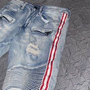 Blue ripped jeans with red stripes on the sides.
